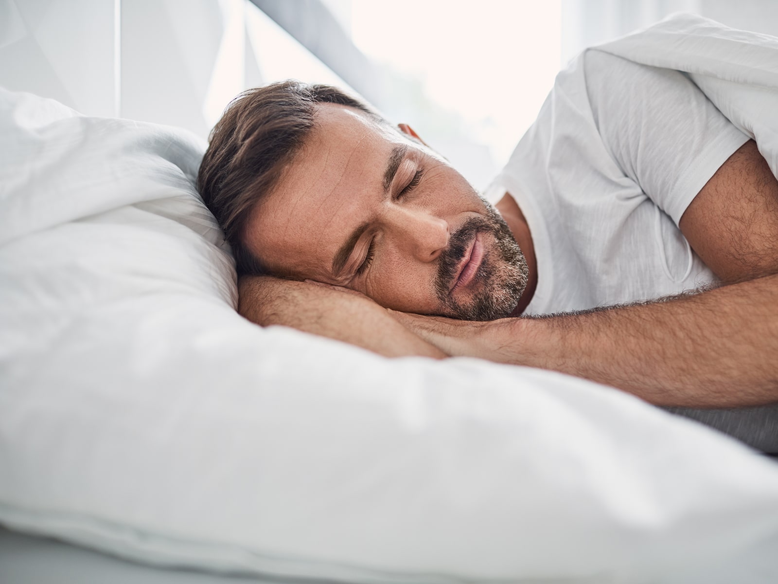 Middle-aged man peacefully sleeping in bed.