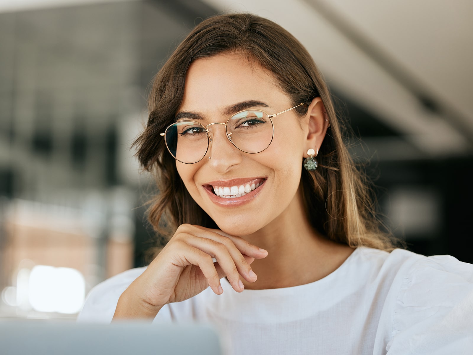Woman in white blouse with glasses showing off her Porcelain Veneers