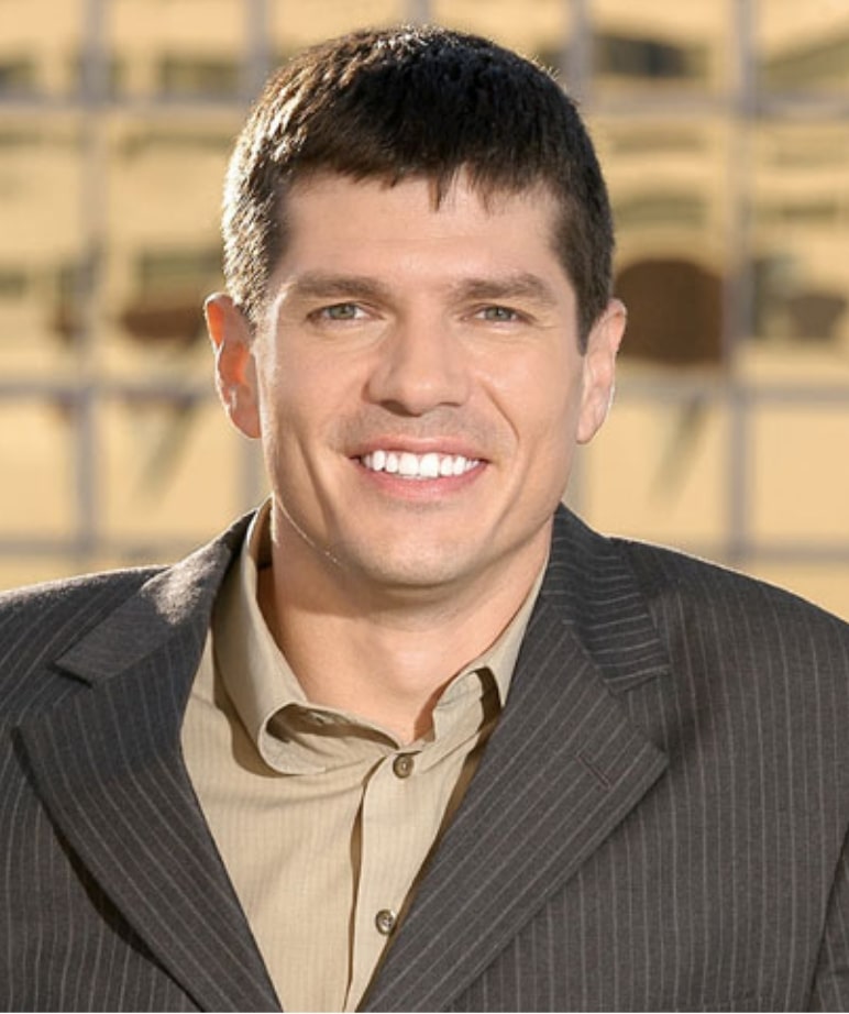 Man wearing a suit with a big smile thanks to his dentist enjoys the beautiful outdoors.