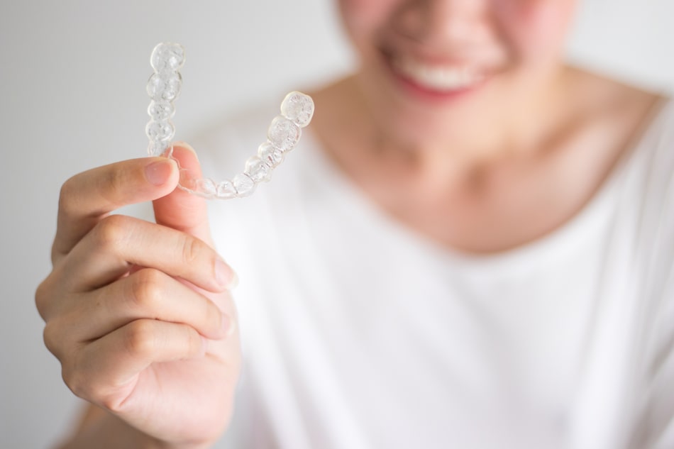 woman holding up Invisalign® clear braces