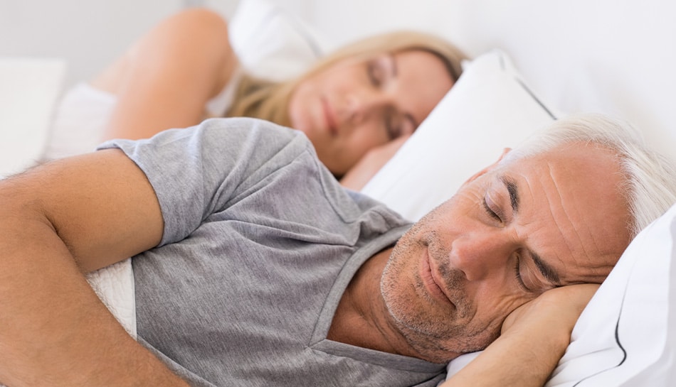 older couple sleeping peacefully in bed next to one another