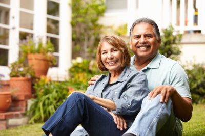 mature couple sitting in grass embracing and posing for photo with smiles