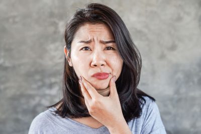 young adult woman holding her jaw in pain