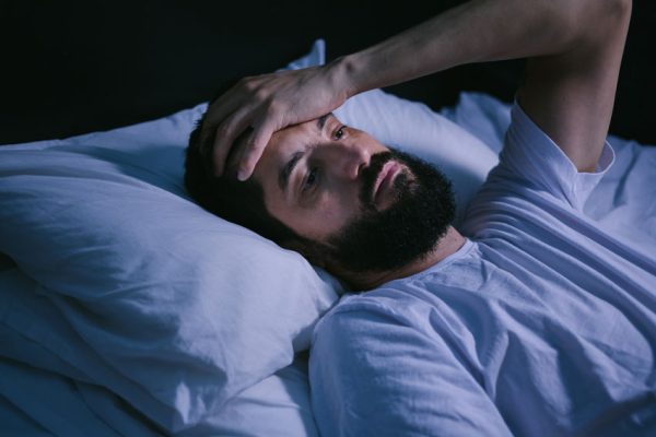 adult man awake in bed, unable to sleep
