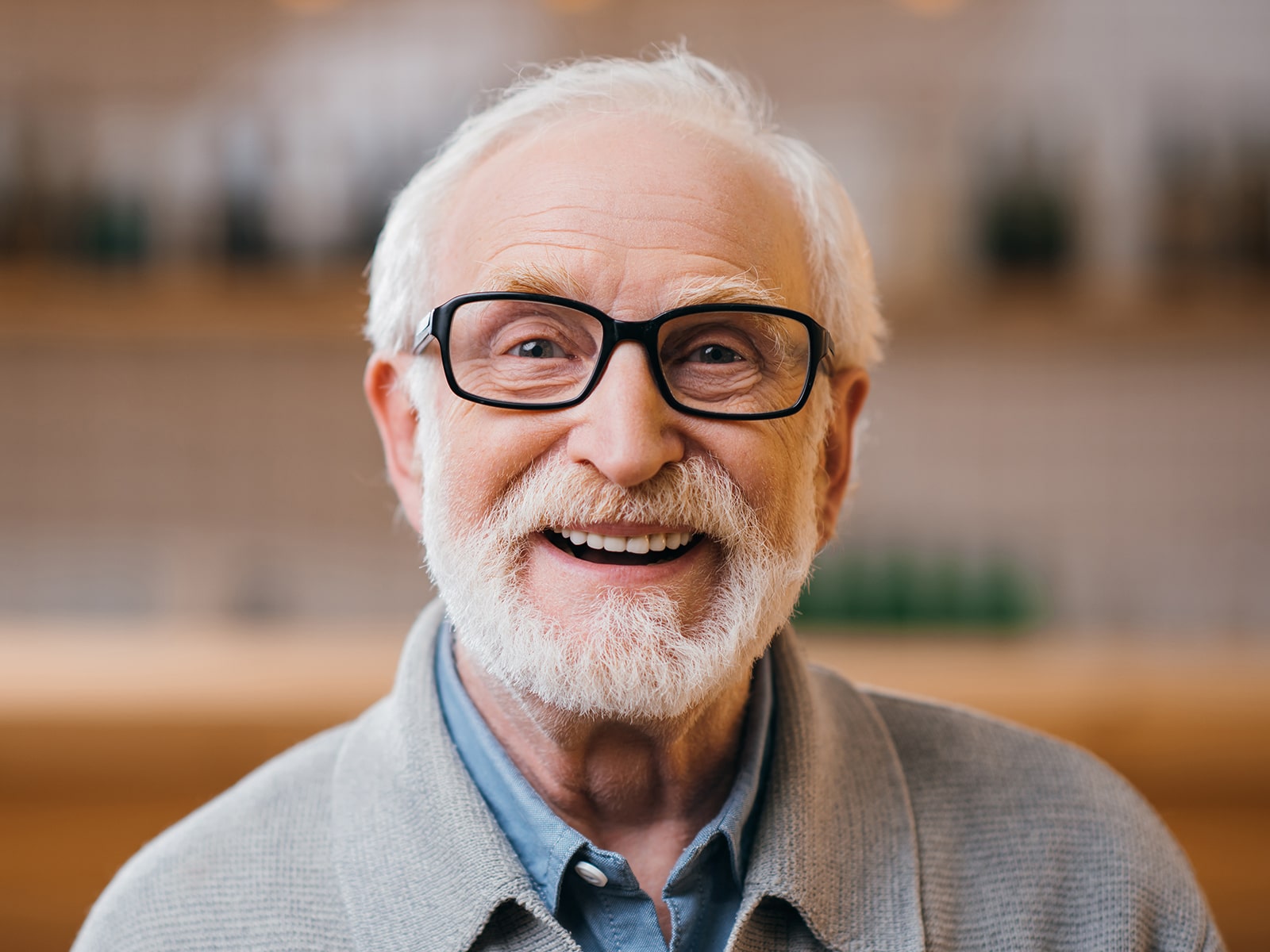 Elderly man with a big smile wearing black glasses.