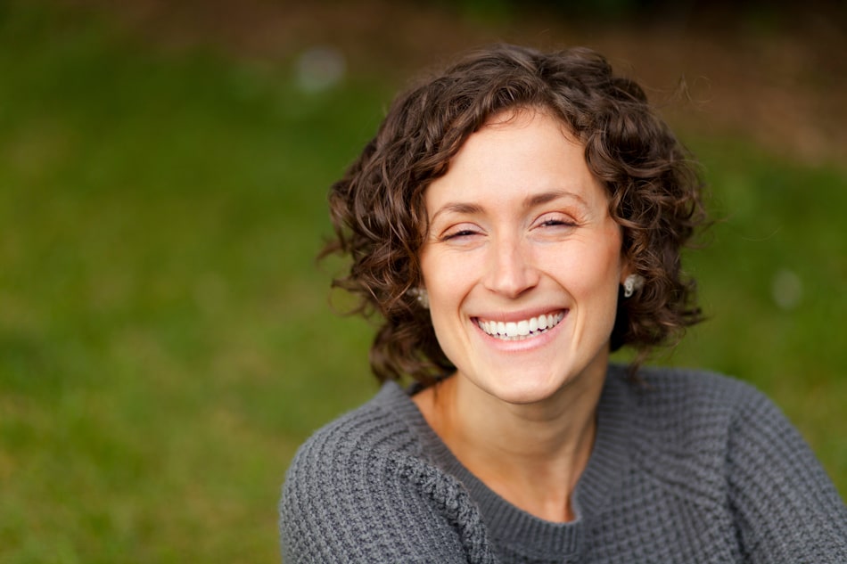 Woman smiling with a green backdrop.